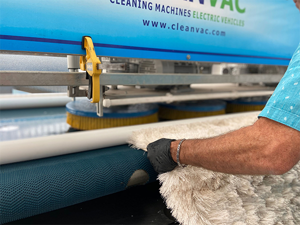 Area rug being guided through professional rug cleaning equipment
